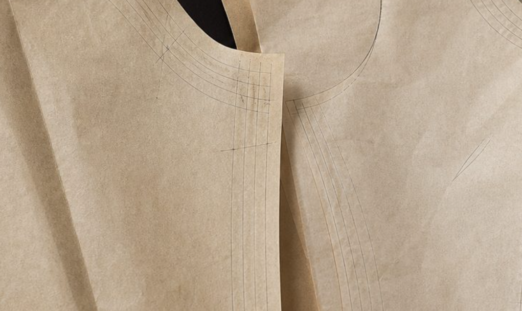 Graded pattern pieces with measuring tape on dark studio surface